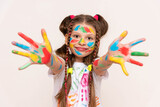 A little girl shows her palms painted with multicolored paints and smiles. A schoolgirl artist draws with her own hands. Creative education of children. White isolated background.
