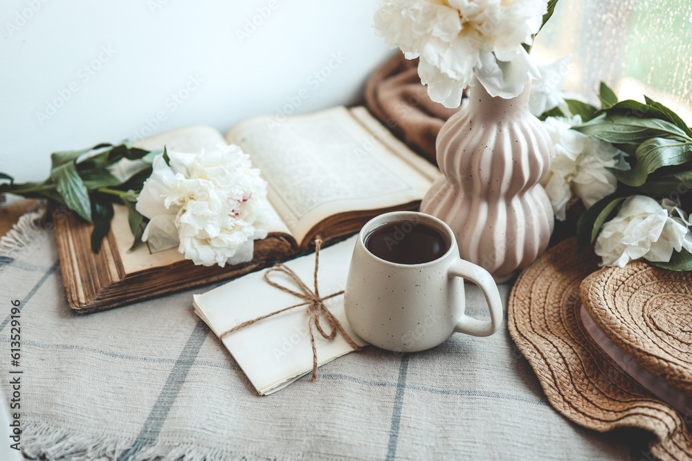 Cup of tea, straw hat, open book and peonies, spring still life Cup of tea, straw hat, open book and peonies, spring still life