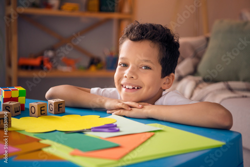 Tableau sur toile Photo of joyful little boy sit nursery table in domestic orphanage doing craft w