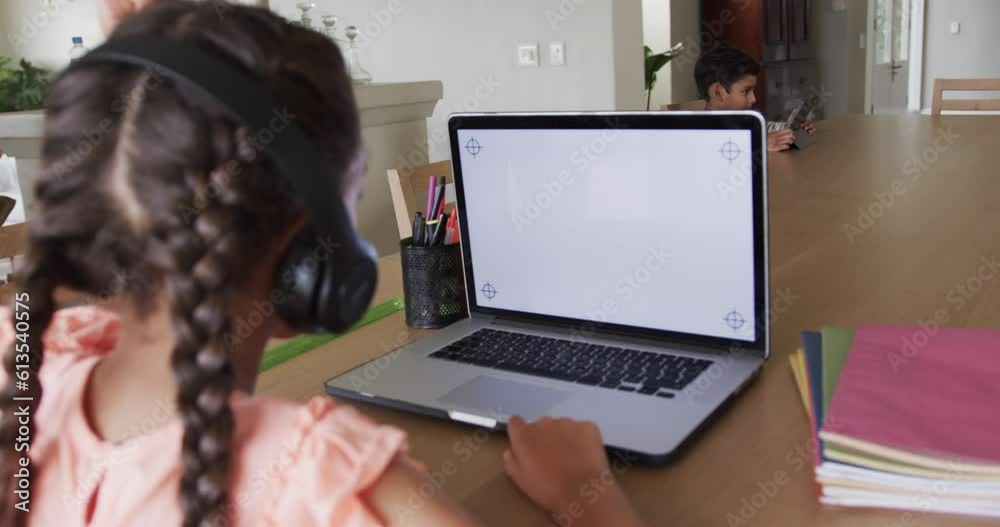 Biracial girl learning online at table using laptop with copy space on screen, slow motion Biracial girl learning online at table using laptop with copy space on screen, slow motion