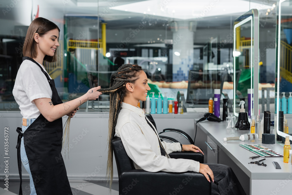 side view, client satisfaction, hairdresser styling hair of female customer, looking at mirror, happy woman with braids, hairstyle, braided hair, beauty salon, hairstyling products