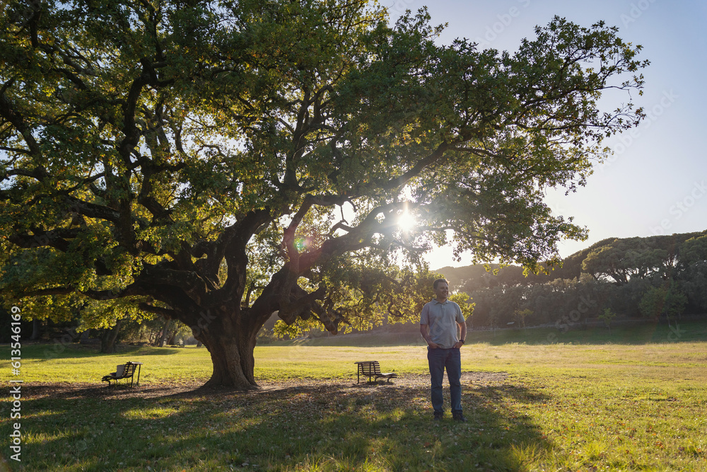 Smiling white man standing under big tree in day lighting Smiling white man standing under big tree in day lighting