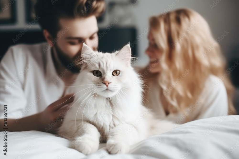 Happy smiling couple and their shaggy cat sitting on the bed, enjoying relaxed morning at home 