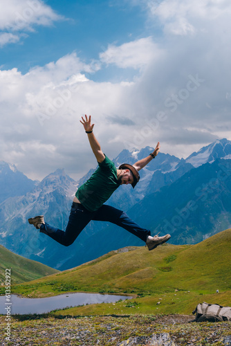 A man tourist fun jump with happines near the Koruldi Lake, Mestia in the Greater Caucasus Mountain Range Upper Svaneti, Georgia. travel and vacation. Summer day. Vertical photo