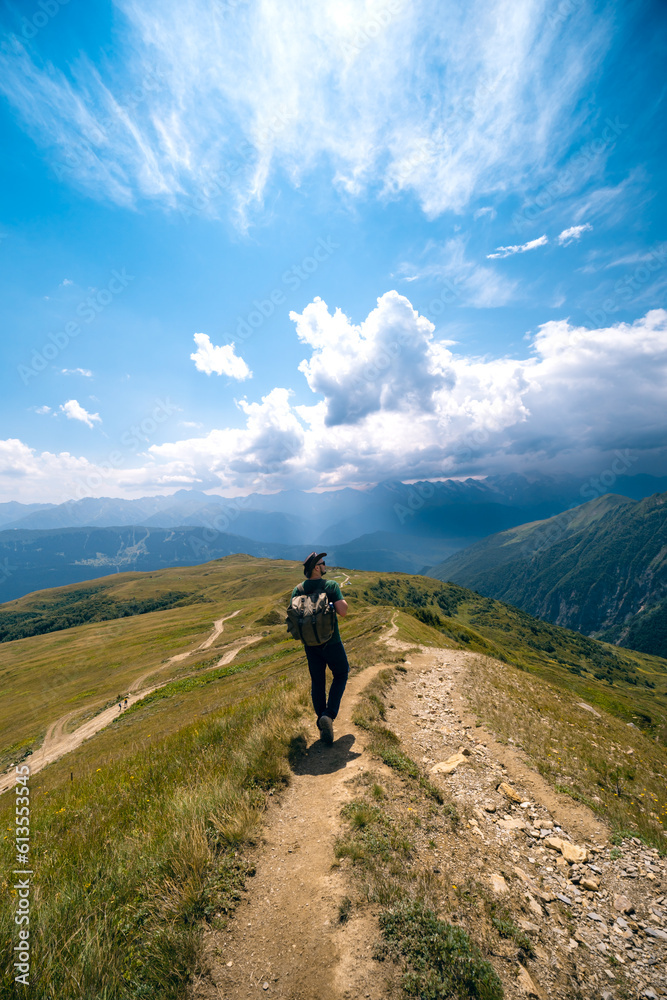 Man hiking to Koruldi lakes, beautiful view of Great Caucasus mountains close to Mestia in Upper Svaneti, Georgia. Summer day. Vertical photo