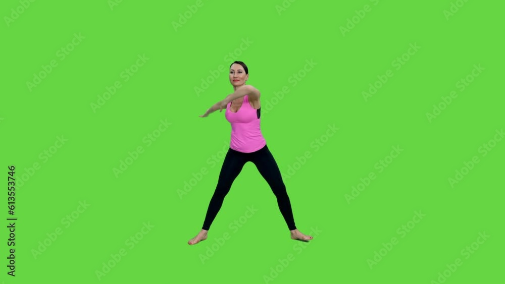 Graceful middle aged woman in pink top practicing fitness standing on green background, chroma key Graceful middle aged woman in pink top practicing fitness standing on green background, chroma key