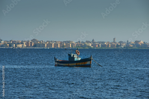 a typical wooden fishing boat with Marsala in the Province of Trapani in Sicily in the background