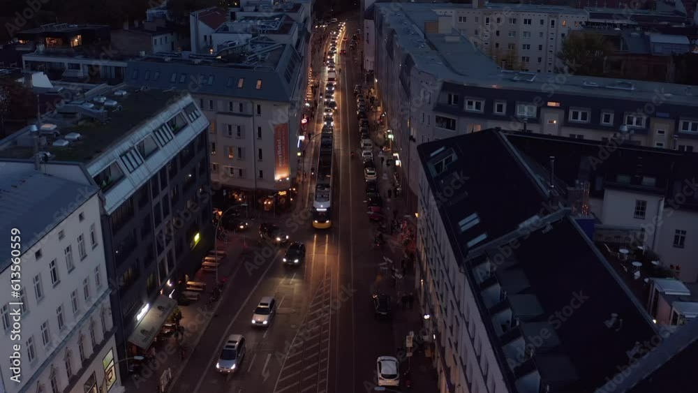 Forwards fly above queue of cars and tram on evening street in city. Vehicles driving on tram tracks in road. Berlin, Germany Forwards fly above queue of cars and tram on evening street in city. Vehicles driving on tram tracks in road. Berlin, Germany