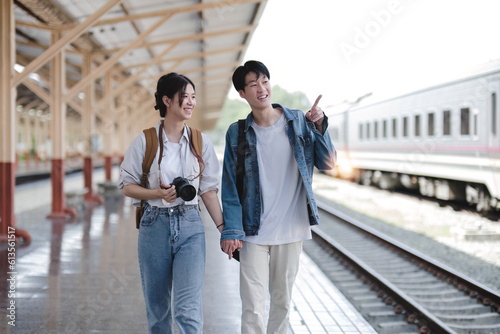 Couple Young asian traveler tourist by train Choose a trip and booking train queue by smartphone. Two Backpacker at platform train station. Happy traveller at railway on vacation holiday weekend. © chartchai