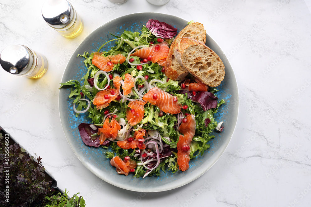 Salad with smoked salmon, onion and pomegranate seeds, served with bread. Healthy lunch with fish, top view. Salad with smoked salmon, onion and pomegranate seeds, served with bread. Healthy lunch with fish, top view.