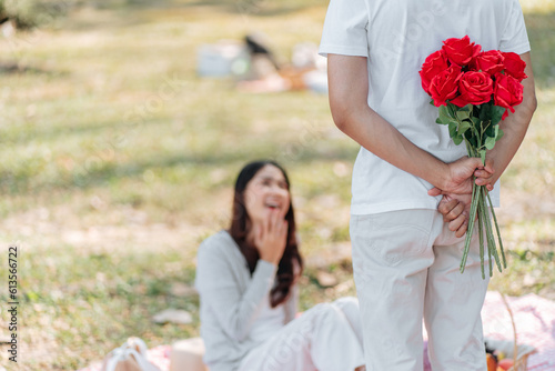 Happy romantic couple in Valentine's Day asian man hiding red rose flower behind for surprise his girlfriend.
