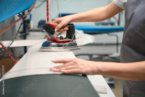 Canvas Print Woman laundry office operator ironing garment, relaxing wrinkles
