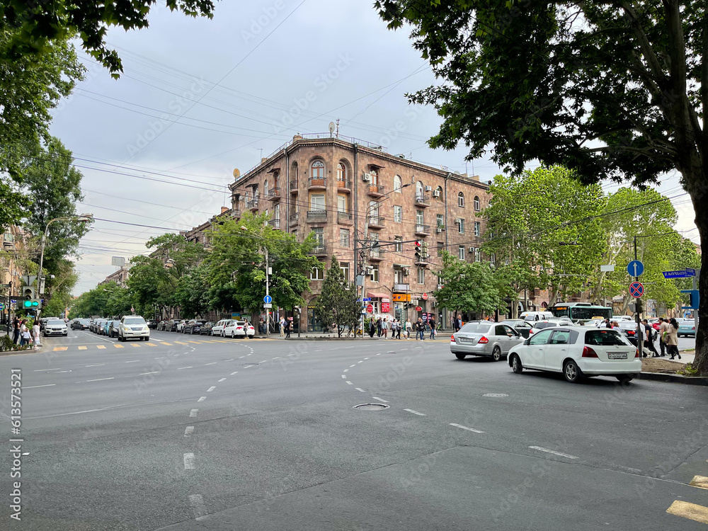 View of Yerevan city. The capital of Armenia. Central part. Busi intersection. Crossroads with people and cars. Summer in Yerevan. Beautiful building in traditional Armenian architectural style.