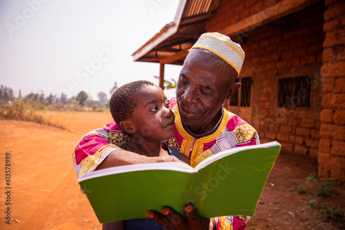 A grandfather reads fairy tales with his grandson in Africa  a moment of affection between grandfather and grandson