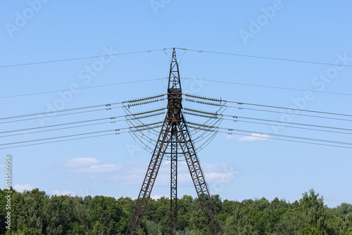 High Voltage Tower supporting the overhead power transmission lines against blue sky.	