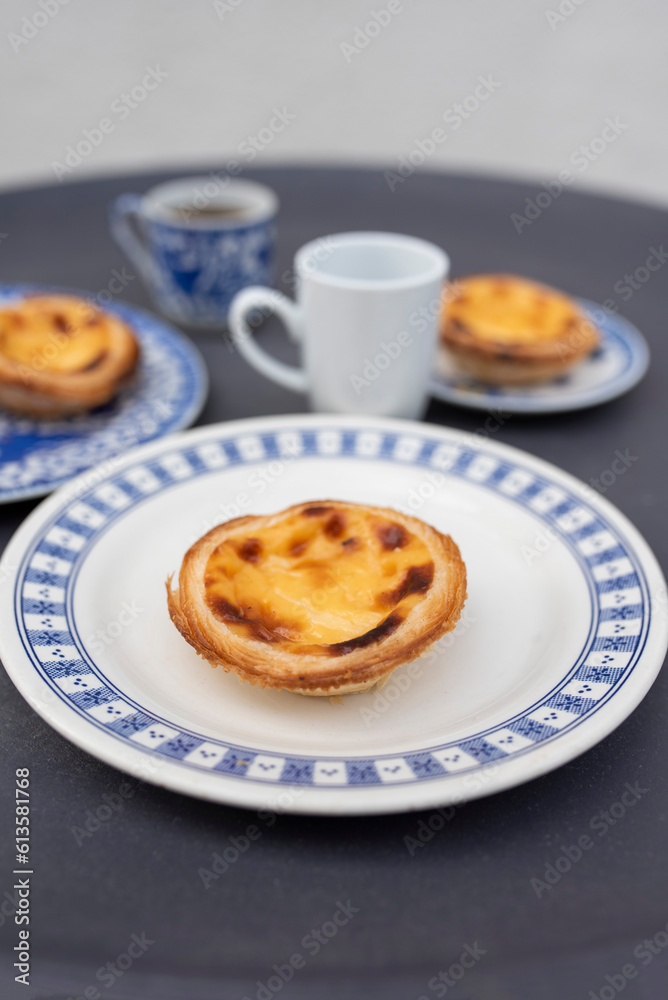 Portugal's traditional sweet dessert Pastel de nata egg custard tart pastry, with coffee on a table in a street cafe Portugal's traditional sweet dessert Pastel de nata egg custard tart pastry, with coffee on a table in a street cafe