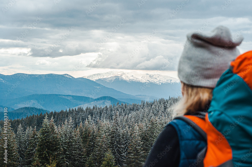 girl looks at snowy mountains and forest, travel, rest, tourist routes in the Carpathians backpack, spring, winter, mental health vacation