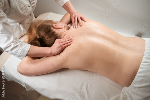 Masseuse female makes manual massage to blonde woman
