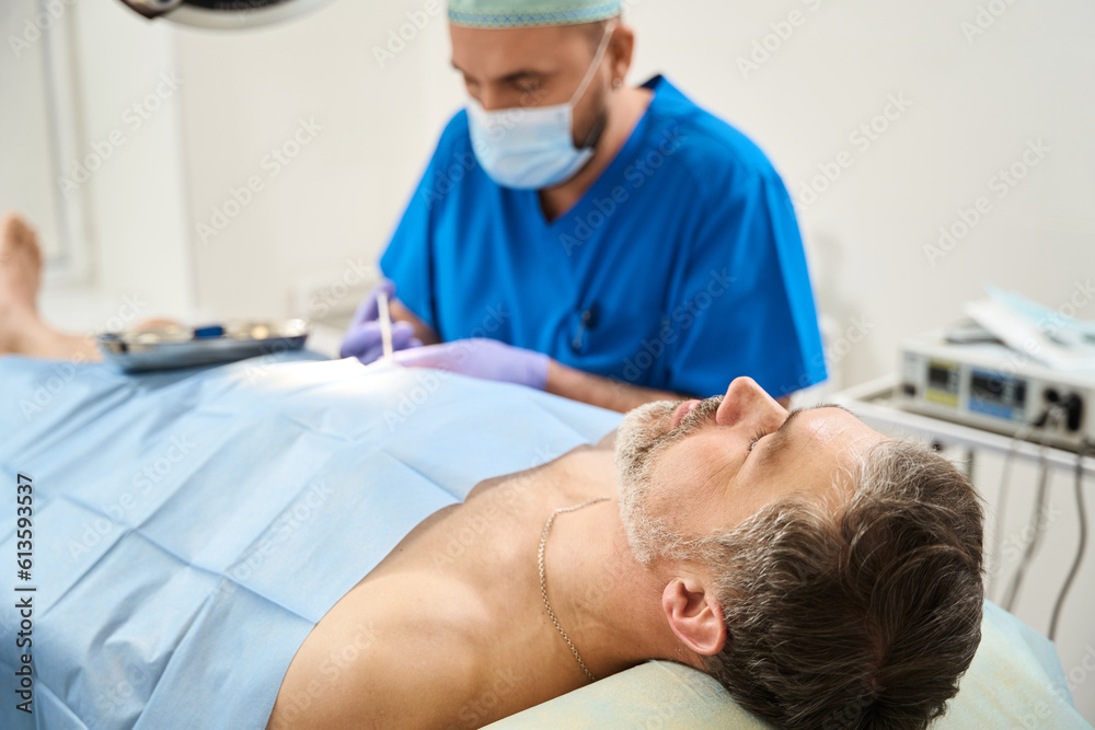 Man on operating table to whom doctor injects with syringe Man on operating table to whom doctor injects with syringe
