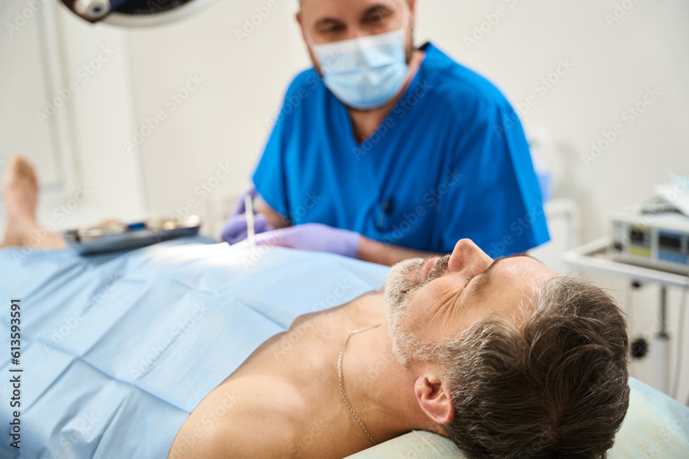 Patient lying on operating table is given injection during surgery Patient lying on operating table is given injection during surgery