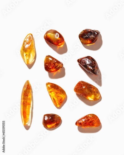 Set of Natural gemstone amber stones with glare shadows, yellow orange isolated on white background. Natural mineral Transparent amber gems different forms, flat lay pattern, minimal top view