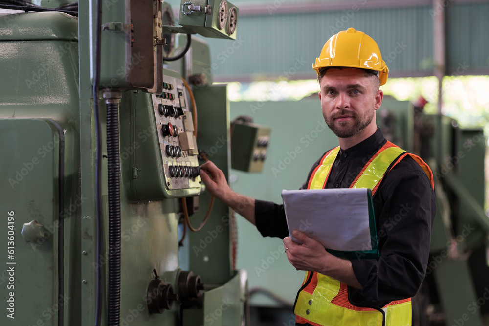 Male engineer worker working and control machine in factory. Male worker working with CNC machine with safety uniform, helmet in industry factory Male engineer worker working and control machine in factory. Male worker working with CNC machine with safety uniform, helmet in industry factory