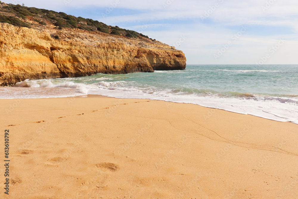 Sandy beach next to a cliff and the ocean on a sunny winter day on the Seven Hanging Valleys Trail in southern Portugal.