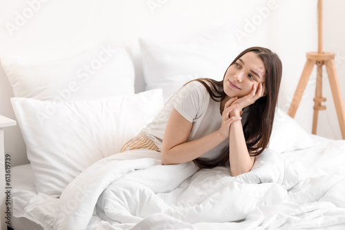 Awaken young woman sitting on bed in morning