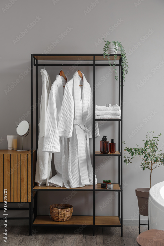 Shelving unit with bathrobes and bath accessories in interior of light room Shelving unit with bathrobes and bath accessories in interior of light room