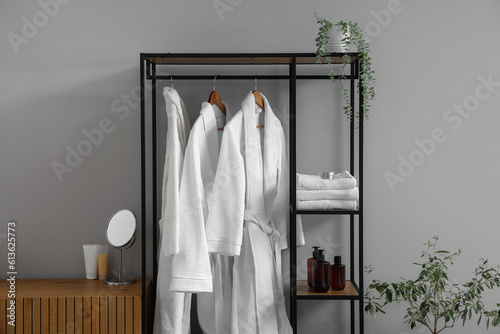 Shelving unit with bathrobes and bath accessories in interior of light room © Pixel-Shot