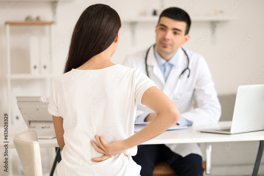 Young woman with bad posture visiting doctor in clinic, back view