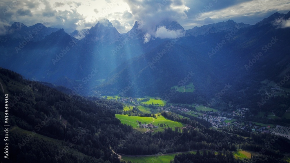 Drone shot of mountains and valley with forest and sun rays in Alps