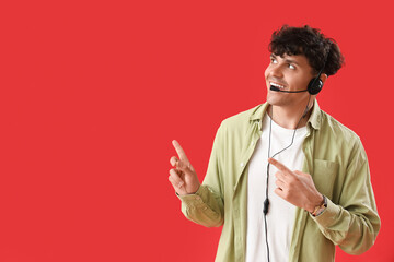 Male technical support agent pointing at something on red background