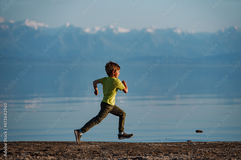 Boy running along the lake shore, Issyk-Kul lake, Kyrgyzstan