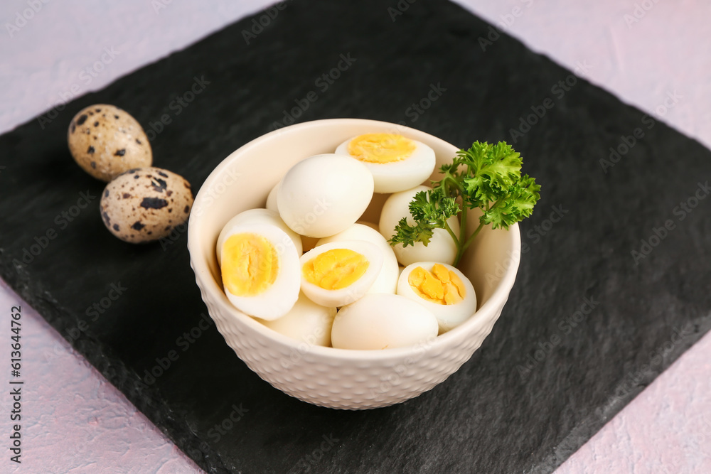 Board with bowl of boiled quail eggs on lilac background Board with bowl of boiled quail eggs on lilac background