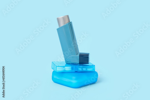 Asthma inhaler and boxes of pills on blue background
