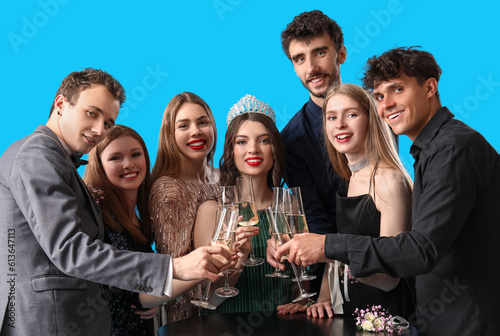 Young people dressed for prom drinking champagne on blue background