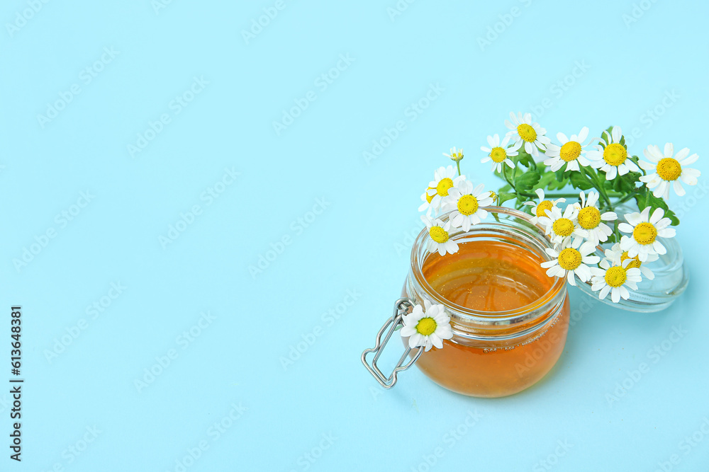 Glass jar of honey and fresh chamomile flowers on color background Glass jar of honey and fresh chamomile flowers on color background