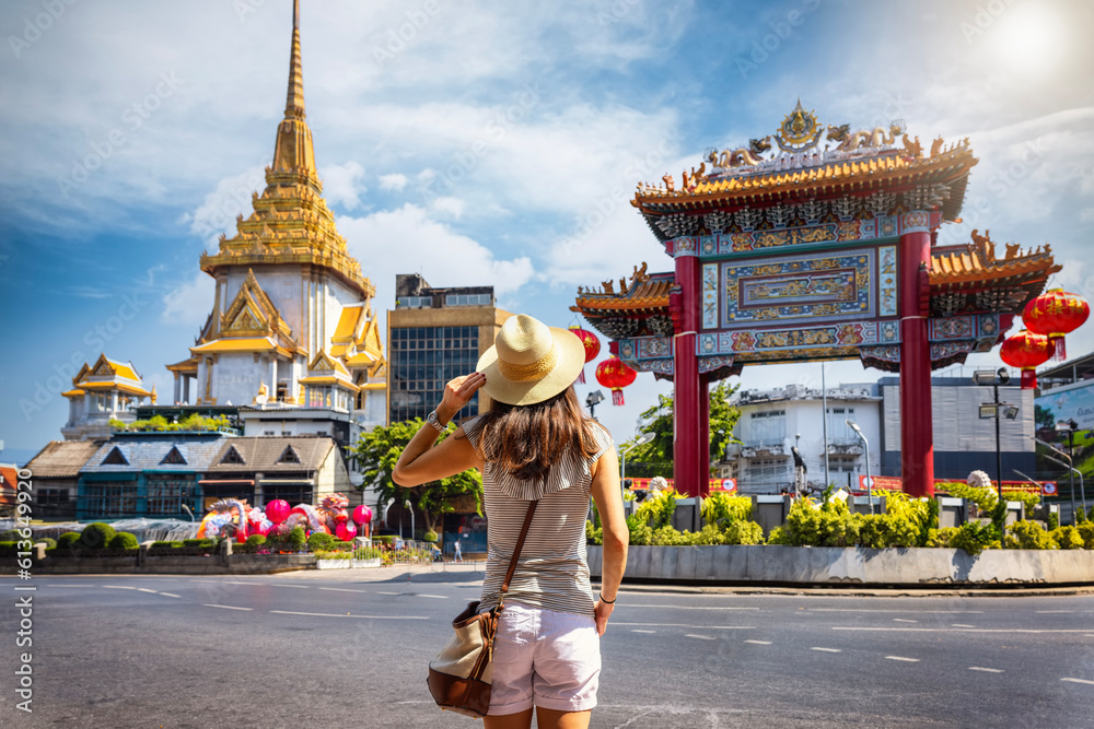 A tourist woman on sightseeing tour stands in front of the Chinatown Gate at the famous Yaowarat Road, Bangkok, Thailand