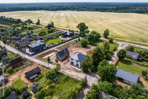 panoramic aerial view of eco village with wooden houses, gravel road, gardens and orchards