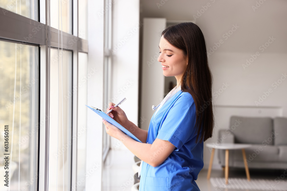 Female medical intern writing in clipboard at hospital Female medical intern writing in clipboard at hospital