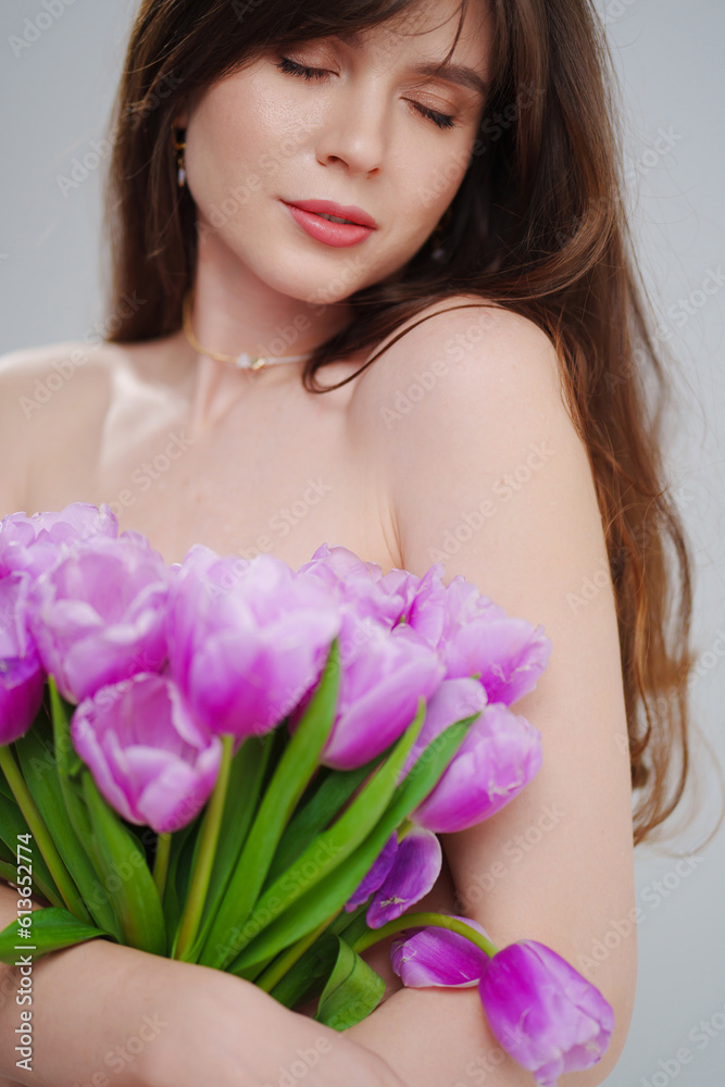 portrait of a beautiful woman topless with tulips on a white background.