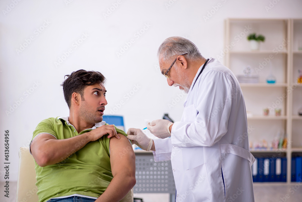 Obraz premium Young male patient visiting old male doctor in vaccination conce