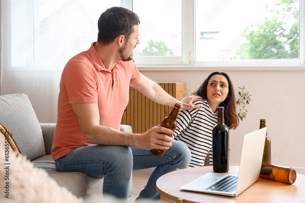 Bruised young woman with her drunk husband at home. Domestic violence concept Bruised young woman with her drunk husband at home. Domestic violence concept