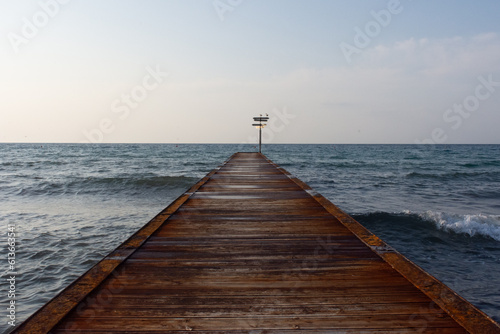 pontile sul mare con cartello e gabbiani