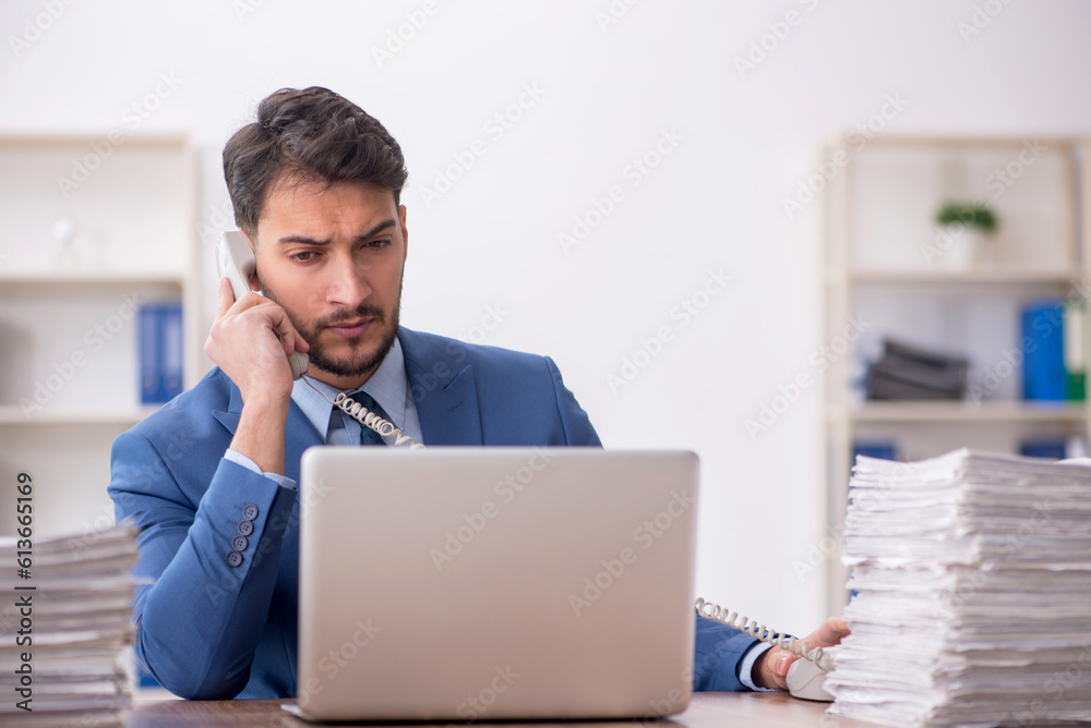 Young male employee and too much work in the office Young male employee and too much work in the office