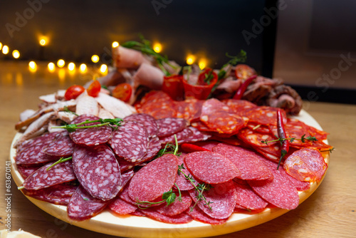 Slices of salami on a wooden board. Assorted charcuterie platter with sliced ham, salami, sausage and spicy chorizo.