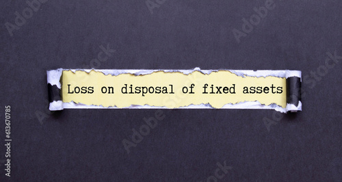 Loss on disposal of fixed assets label on notepad with laptop and smartphone on wooden table.