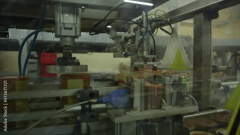 static medium shot of a robotic machine putting plastic caps on cracker packages in a food factory static medium shot of a robotic machine putting plastic caps on cracker packages in a food factory