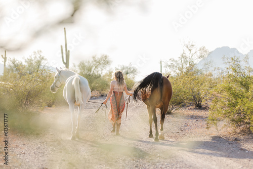 cowgirl walking into the sunset with her horses in the Arizona desert